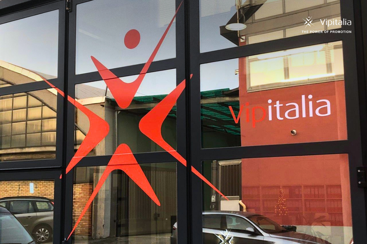 Custom glass window branding with company logo applied on office entrance gate as a vinyl vetrofania, made by Vipitalia.